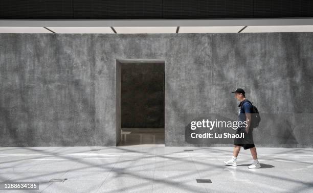 asian men walk past gray concrete walls - walking past office wall stock pictures, royalty-free photos & images
