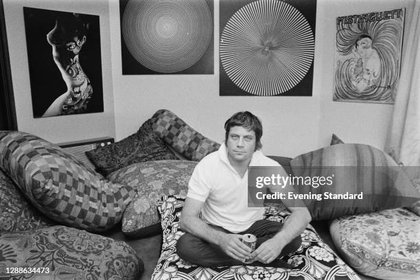 English actor Oliver Reed , UK, 1971. He is drinking a can of Coca-Cola, and on the wall to the right is a poster of French actress and singer...