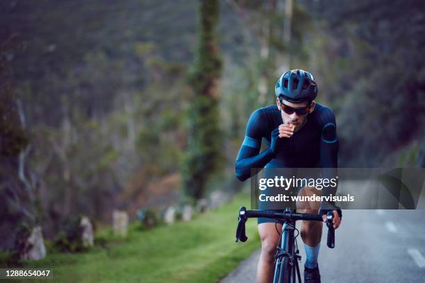 giovane ciclista in bicicletta e mangiare snack bar all'aperto - sportman foto e immagini stock