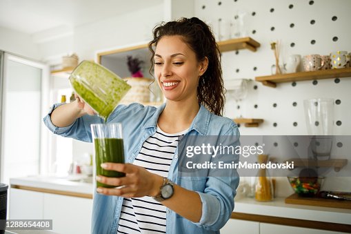 Young woman preparing a green smoothie at home Young woman preparing a green smoothie at home