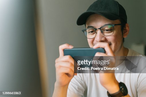 Asian Man Is Playing Mobile Game Seriously. Stock Photo, Picture