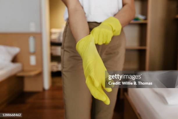 close up of maid putting on rubber gloves - yellow glove stock pictures, royalty-free photos & images