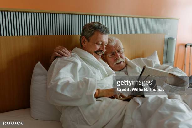 Mature Gay Couple Watching Film In Bed Together
