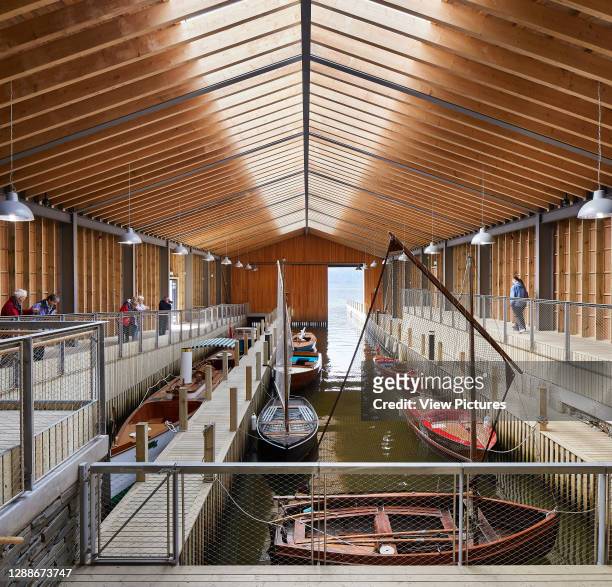 Boathouse with timber walkways and vessels. Windermere Jetty Museum, Windermere, United Kingdom. Architect: Carmody Groarke, 2019.