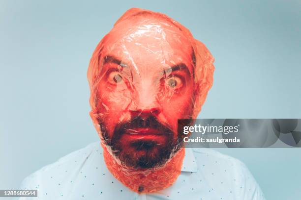 scary portrait of mid adult man with red cellophane on his head - cellophane stock pictures, royalty-free photos & images