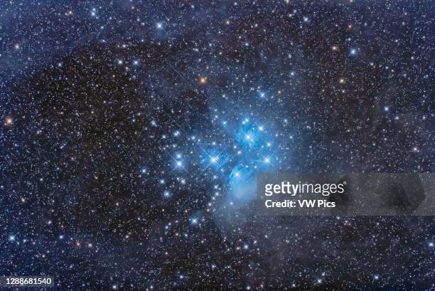 The Pleiades star cluster, Messier 45, amid the faint and dusty nebulosity that surrounds it. The stars of the Pleiades are passing through the dust...