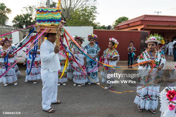 Women in tradtional festive embroidered huipils and flowered hats prepare for the Dance of the Pig's Head and of the Turkey, or Baile de la cabeza...