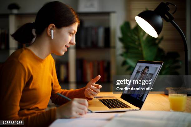 smiling teenage girl with bluetooth headphones having video call on laptop computer at home - lecturer online stock pictures, royalty-free photos & images