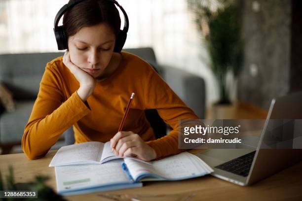 bored teenage girl with headphones studying at home - kid headphones stock pictures, royalty-free photos & images