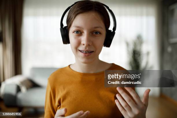 portret van glimlachend tienermeisje met draadloze hoofdtelefoon die videovraag thuis heeft - very young webcam girls stockfoto's en -beelden