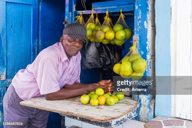 Old local black man selling oranges and lemons at market in the city Georgetown, Demerara-Mahaica region, Guyana, South America .