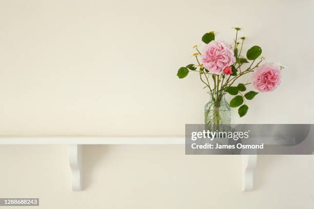 vase of roses and daisies on the mantlepiece shelf of a listed period cottage. - rosa mantel stock pictures, royalty-free photos & images