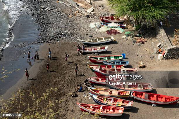 Youth playing soccer on the beach in front of traditional wooden fishing boats, Cidade Velha on the island of Santiago, Cape Verde / Cabo Verde.