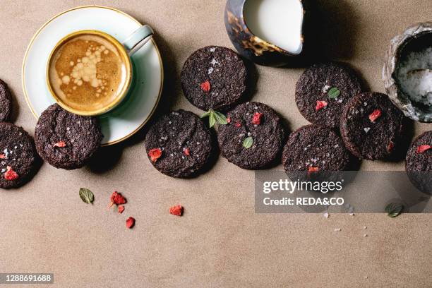 Homemade dark chocolate salted brownies cookies decorated by dry and fresh raspberries, served with salt flakes, berries, mint, milk and cup of...