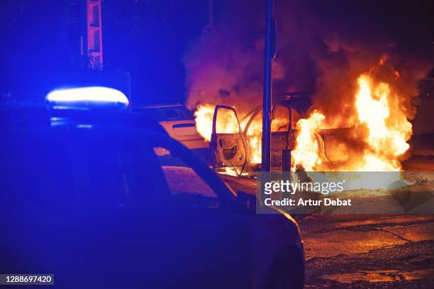 police action during emergency with car in flames at night. - riot stock pictures, royalty-free photos & images