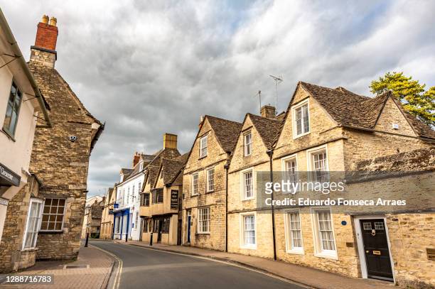 narrow street and stone residential buildings against an overcast sky - cirencester stock pictures, royalty-free photos & images