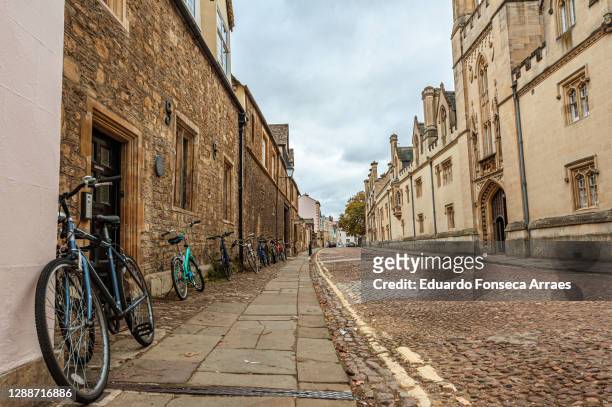 old cobblestone street lined by stone buildings and bicycles, against an overcast sky - oxford engeland stockfoto's en -beelden