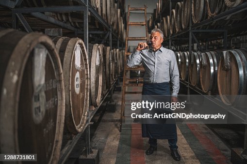 Senior sommelier tasting red wine in wine cellar. Senior sommelier tasting red wine in wine cellar.