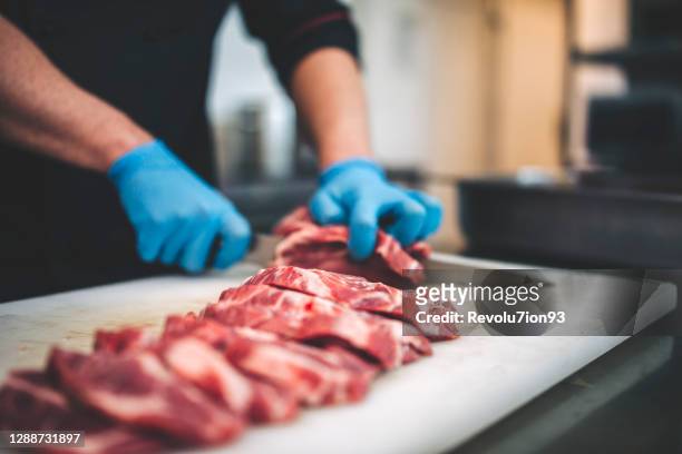 männlicher metzger schneidet rohes fleisch mit scharfem messer in restaurants küche - butcher knife stock-fotos und bilder