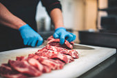 Male butcher cut raw meat with sharp knife in restaurants kitchen