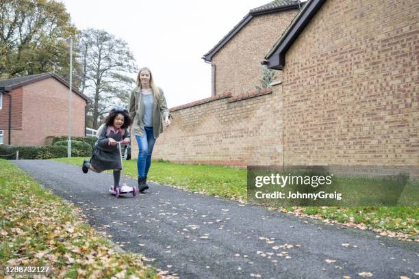 moeder en energieke jonge meisje berijdende scooter aan school - hampshire stockfoto's en -beelden