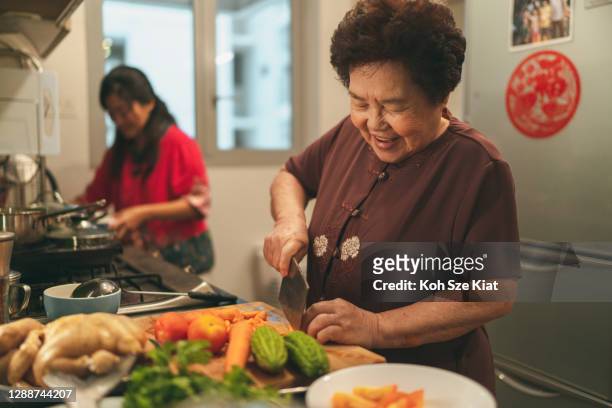 senior asiatische frau und ihre tochter vorbereitung essen für ihre familie treffen abendessen am chinesischen silvesterabend - 40 year old female stock-fotos und bilder