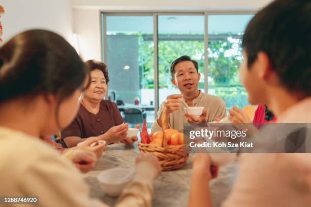 Familia asiática comiendo tang yuan o bola de arroz glutinoso durante el Año Nuevo Chino