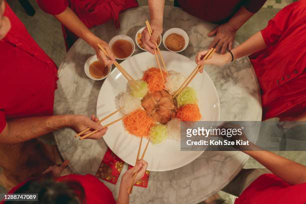 multi generation family celebrates chinese traditional new year with a prosperity toss or “yee sang” - prosperity toss stock pictures, royalty-free photos & images