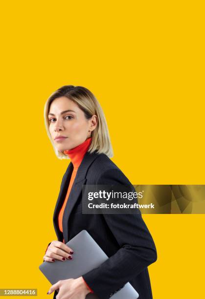 confident businesswoman wearing suit while holding laptop over gray background - laptop coloured background stock pictures, royalty-free photos & images