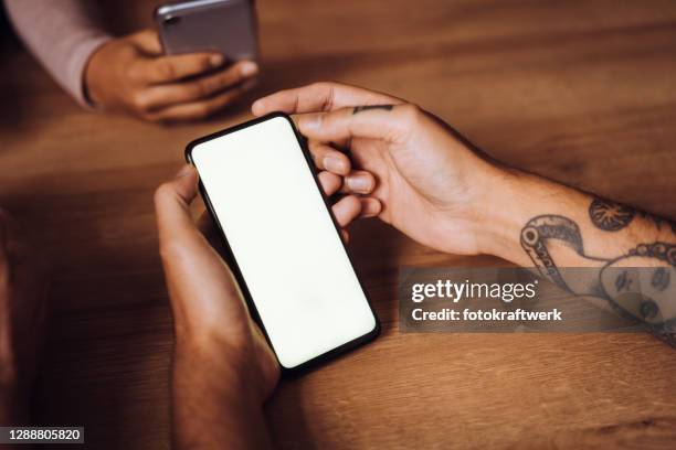 bijgesneden handen van jonge mens die mobiele telefoon met vrouwelijke vriend op lijst in koffie gebruikt - man holding his hand out stockfoto's en -beelden