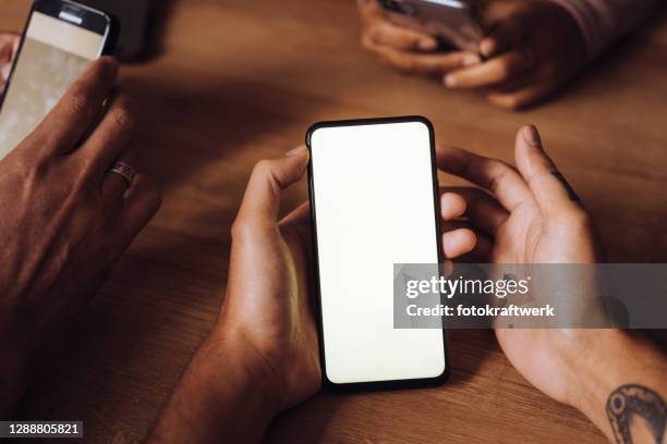 hands of friends using mobile phones on table in restaurant at weekend - three people at table stock pictures, royalty-free photos & images