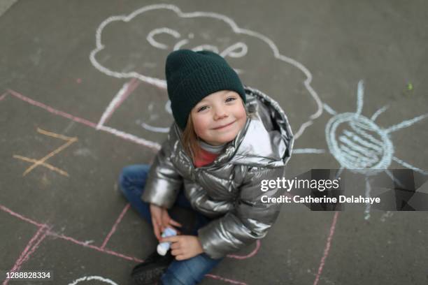 a 5 year old little girl drawing with a chalk stick in the street - city year stock-fotos und bilder