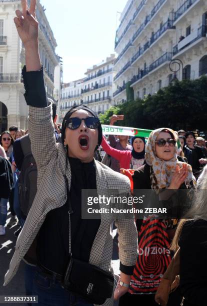 Une femme bras levé fait le V de victoire parmi d'autres femmes algériennes lors de la manifestation pour la Journée Internationale pour les Droits...