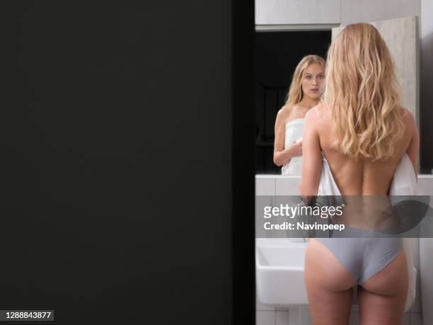 beautiful blond woman standing half naked in front of the mirror - young women no clothes stock pictures, royalty-free photos & images