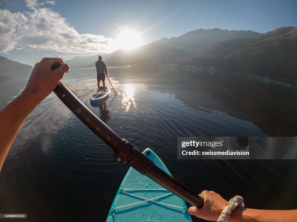 Ponto de vista da primeira pessoa de uma mulher remando em uma prancha de stand up paddle