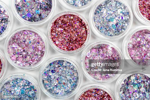 blue, pink and red glitter in jars on white background. shiny holographic elements, sparkle. beautiful shimmer for manicure, makeup, nail extension, design. cosmetic products. trendy delicate colors. - face painting stock pictures, royalty-free photos & images