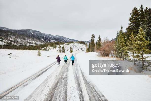 Three female friends on winter run on snowy road