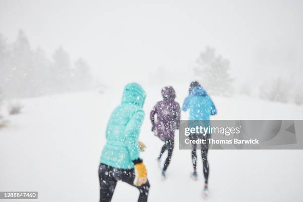 defocused image of three woman running together in snow storm - weather improve in kashmir after two days of snowfall stockfoto's en -beelden