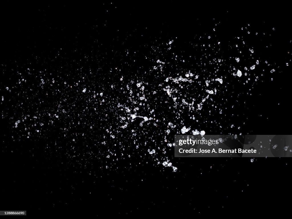 Splashes, jets and drops of water in motion suspended in the air on a black background.