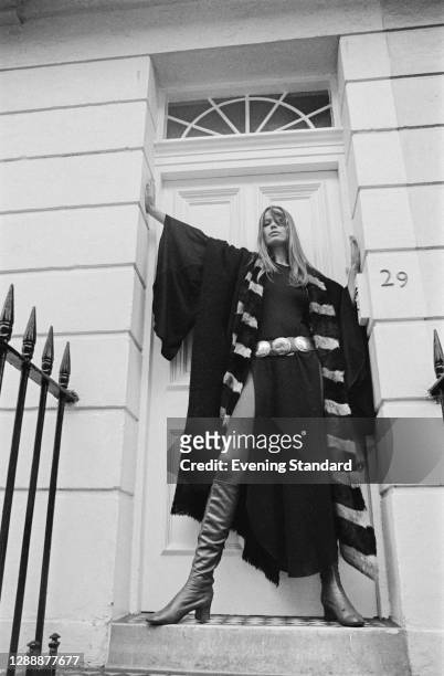 German model Veruschka von Lehndorff wearing an academic-style robe over a belted dress and boots, UK, October 1971.