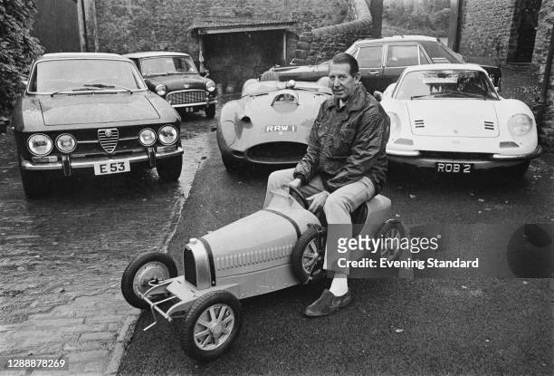 Formula One team owner Rob Walker at home in Nunney, Somerset, with a model formula one car and some of his of real motorcars, UK, October 1971. From...