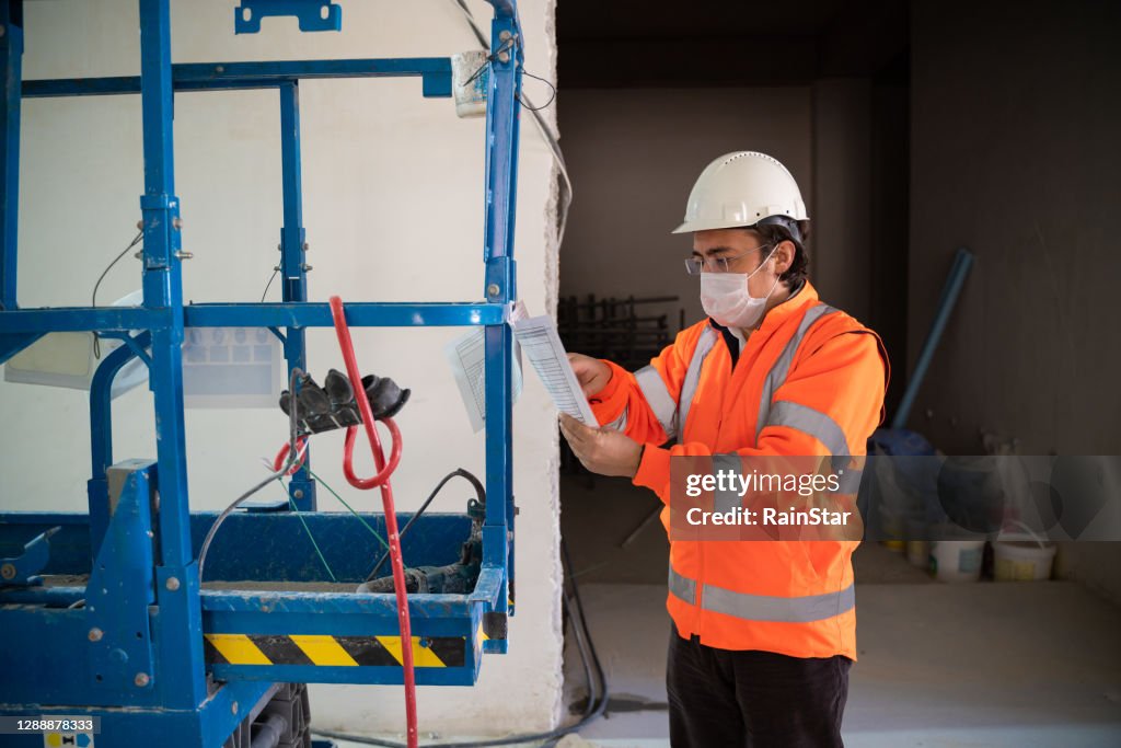 Male engineer checks documents on forklifts used in the factory where he works