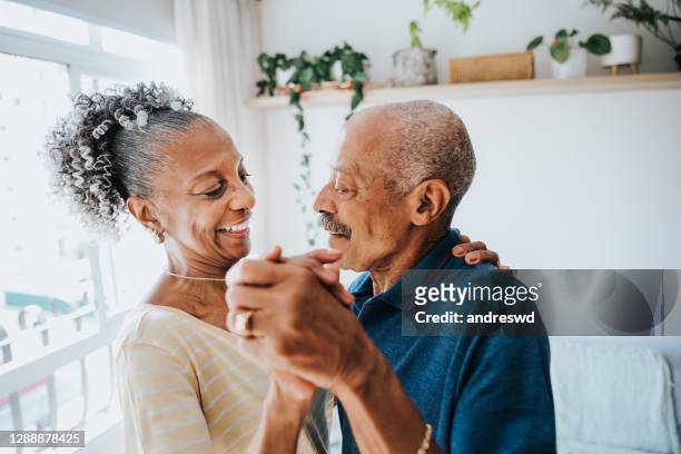 coppia senior che balla in camera di casa abbracciando e spensierata - coppia anziana foto e immagini stock