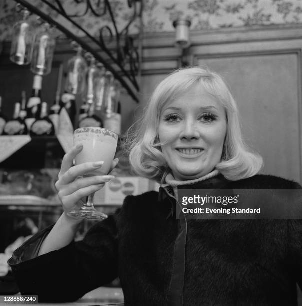 English singer Janie Jones celebrates with a drink after being acquitted on vice charges, UK, 18th May 1967.