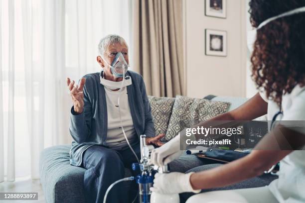 mujer mayor con una máscara de oxígeno hablando con un médico - medical oxygen equipment fotografías e imágenes de stock