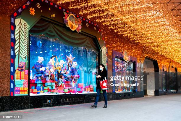 a woman walking in front of galeries lafayette department store windows, closed during second lockdown of covid19 - intercontinental paris grand stock pictures, royalty-free photos & images