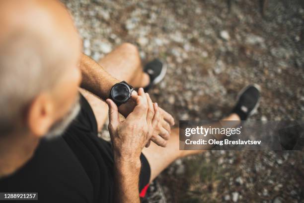 man using fitness tracker or smart watch before run training outdoors. close-up photo with dark background. - marathon start stock pictures, royalty-free photos & images