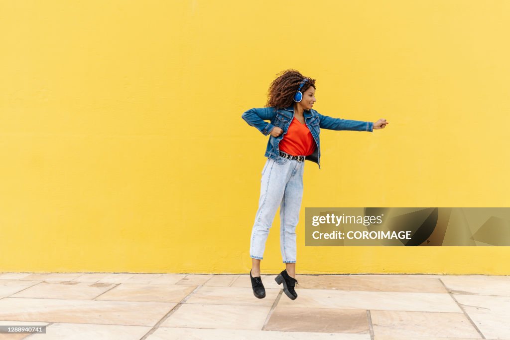 Excited Black Woman Jumping Against Yellow Wall High-Res Stock Photo ...