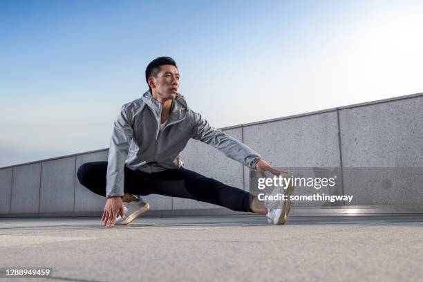 走る前に伸びる若いアジア人男性 - 美脚 ストックフォトと画像