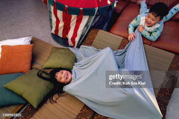 Hermanos asiáticos jugando cansados antes de acostarse durante una estancia en casa acampando